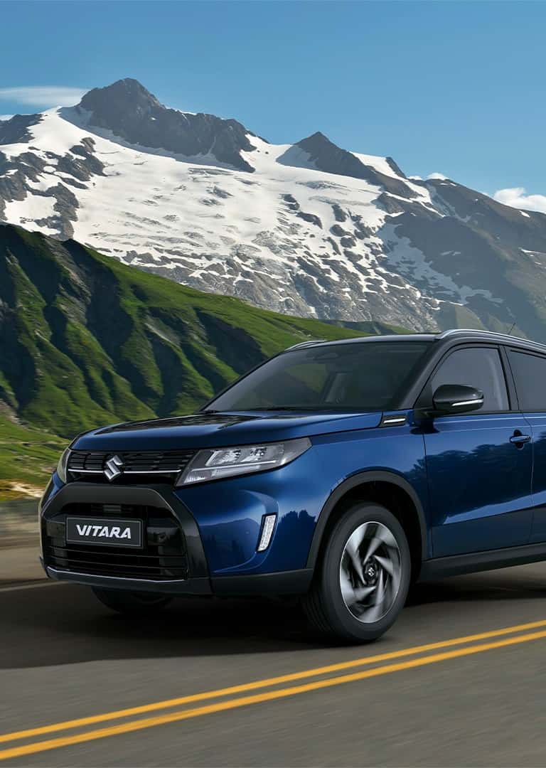 Suzuki Vitara hibrid indigókék gyöngyház és kozmikusfekete gyöngymetál fényezésben, hegyvidéki táj előtt